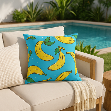 Blue pillow with banana pattern on a beige couch by a pool